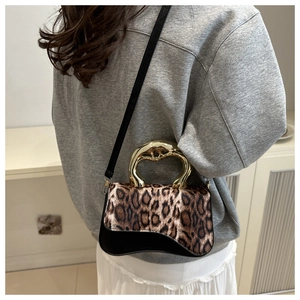 Detail of leopard print crossbody bag featuring a unique gold metallic handle on a model