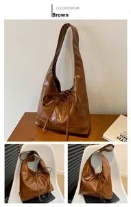 Detail of a brown ruched tote bag with decorative bow tie and smooth leather texture