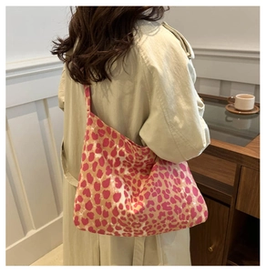 Close-up of leopard print canvas tote bag with pink and orange patterns on a model
