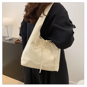 Minimalist beige leather tote bag with bow drawstring on model in home setting