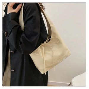Side view of creamy white leather tote bag with stylish fringe tassels and bow detail