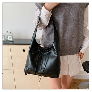 Detailed view of black faux leather tote bag with bow detail and reinforced bottom