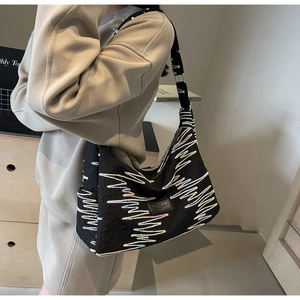 Detail of black jacquard shoulder bag featuring colorful wavy embroidery and adjustable strap