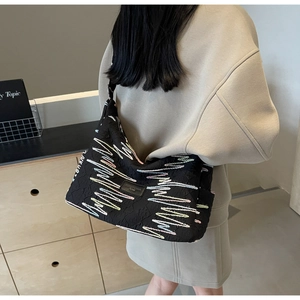 Detail of black canvas tote bag with multi-color wavy embroidery and brand label