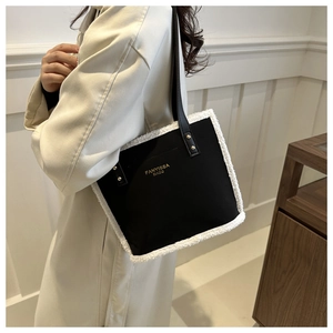 Close-up of black tote bag with white faux fur trim and gold FANYISSA BAGS logo details