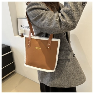 Brown bucket bag with white faux fur trim and adjustable leather strap on model shoulder