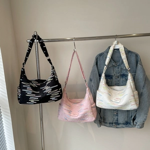 Three crescent-shaped canvas crossbody bags in black, pink, and white with wave patterns