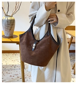 Detail of a dark brown suede tote bag featuring a metal clasp and leather shoulder straps