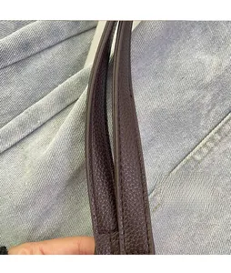 Detail of dark brown leather straps with litchi texture and neat stitching on a tote bag