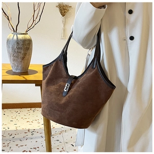 Detail of dark brown suede tote bag featuring silver metal buckle and premium leather piping