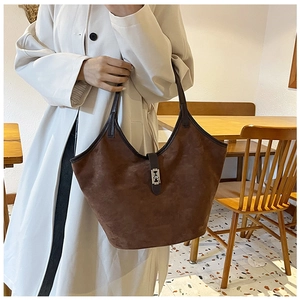 Detail of dark brown suede tote bag featuring silver twist lock and leather handles