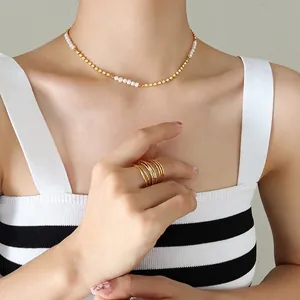 Collier élégant perles d'eau douce et cubes dorés porté avec une bague large minimaliste
