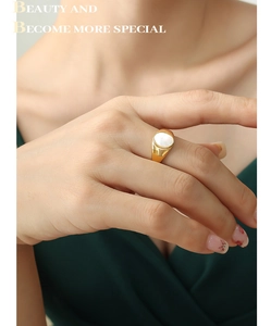 Close-up of gold titanium ring with oval white seashell inlay on a woman's hand