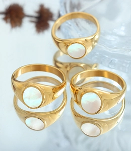 Detailed view of three gold-plated titanium steel rings with white shell inlays on blue mirror