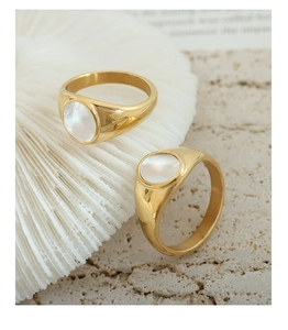 Detail of gold-plated rings with natural white mother of pearl inlay on marble