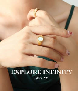 Detailed view of two gold-plated rings featuring oval white mother-of-pearl inlays on a hand