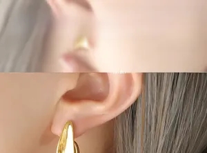 Close-up of polished gold-tone J-shape earrings showcasing the streamlined metal teardrop