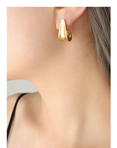 Close-up of minimalist gold-plated J-shaped twisted earrings worn by a model