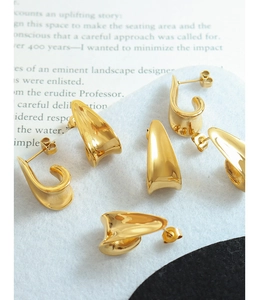 Close-up of polished gold-plated J-shaped earrings on a stylish magazine background