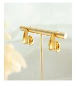 Detailed view of gold irregular J-shape curved earring on a T-stand minimalist display