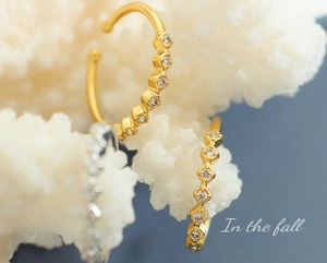 Macro detail of gold geometric square rings with sparkling cubic zirconia on coral