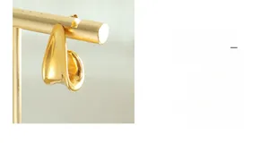 Detailed macro shot of gold plated J-shaped earring with polished mirror finish