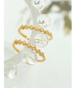 Detailed view of two wavy gold rings with pavé cubic zirconia on textured glass
