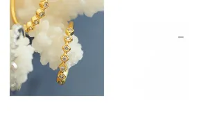 Detail of gold plated ring with seven cubic zirconia stones on wave pattern texture