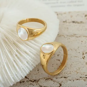 18K gold plated titanium rings with natural white shell inlay on a stone pedestal