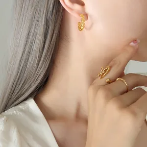 Orecchini a cerchio dorati a forma di conchiglia e anelli su modella femminile