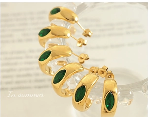 Gros plan de boucles d'oreilles en or 18K en forme de C avec zircon émeraude marquise