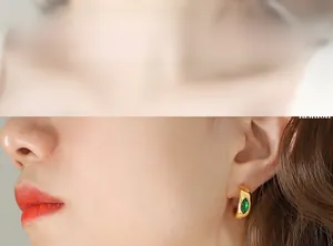 Détail d'un modèle portant une boucle d'oreille dorée en C avec zircon vert marquise
