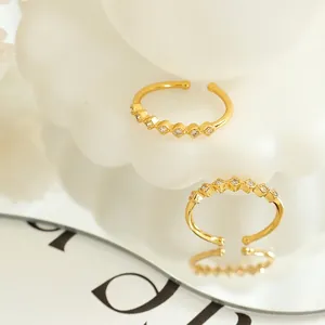 Golden geometric square zircon open brass rings shown on floral stand with reflection