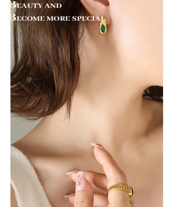 Détail des boucles d'oreilles en forme de C plaquées or 18 carats avec zircon vert émeraude