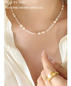 Dettaglio della collana con perle d'acqua dolce e anello dorato su camicia bianca
