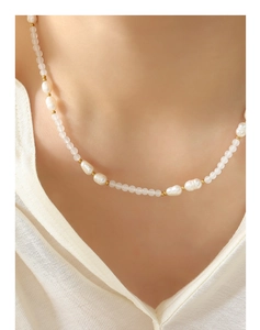 Dettaglio della collana con perle d'acqua dolce e giada bianca su camicia bianca