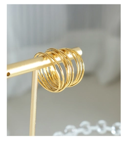 Minimalist gold-plated stackable rings displayed on a golden T-stand with warm lighting