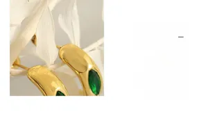 Gros plan détaillé de boucles d'oreilles dorées en titane avec zircone verte