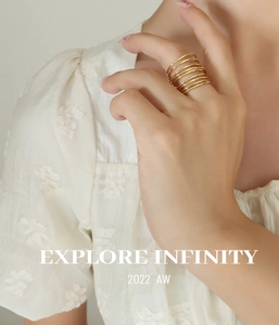 Close-up of golden multi-layer spring style brass ring worn by model with lace sleeve