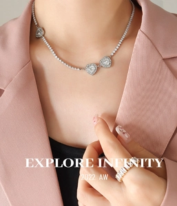 Dettaglio collana con cuore di zirconi e anello su modella in blazer rosa