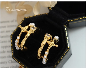 Macro shot of French vintage C-shape earrings with imitation pearls and zircons in a box