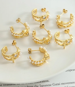 Macro detail of French vintage irregular C-shape hoop earrings with pearls and zircon