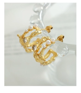 Macro detail of French vintage C-shape gold earrings with pearls and zircons