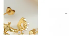 Macro shot of French vintage C-shaped gold earrings featuring pearl and zircon inlay details