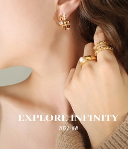 Detail of French vintage C-shaped pearl earrings and gold textured rings on a model