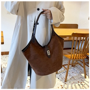Detail showing brown suede tote bag with leather strap and silver buckle on a stylish model