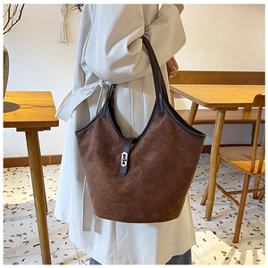 Detail of large brown suede tote bag featuring a leather handle and metallic decorative buckle
