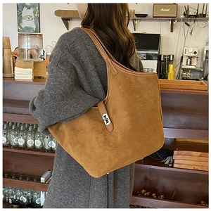 Detail of a large brown suede tote bag featuring a silver metal buckle in a vintage style