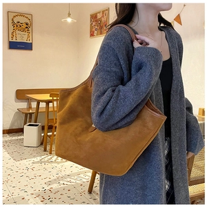 Large caramel suede tote bag shown on model in a cozy cafe setting for daily commute