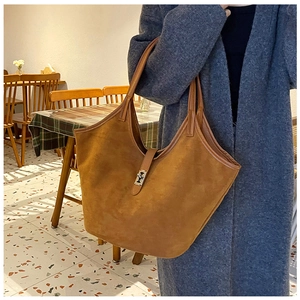 Detail of a brown suede tote bag with a silver metal clasp for women in a cafe setting